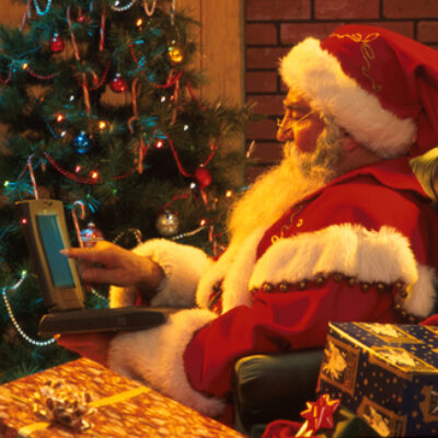 Santa Claus Typing on Laptop Computer W/ Presents & TreeInside Home Christmas